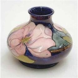 A Moorcroft squat vase with magnolia on a...