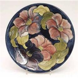 A Moorcroft plate with clematis on a dark...