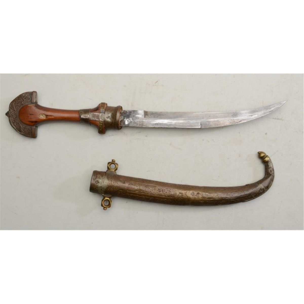 Older IndoChinese curved blade belt knife with wood grip and hammered brass sheath with some old