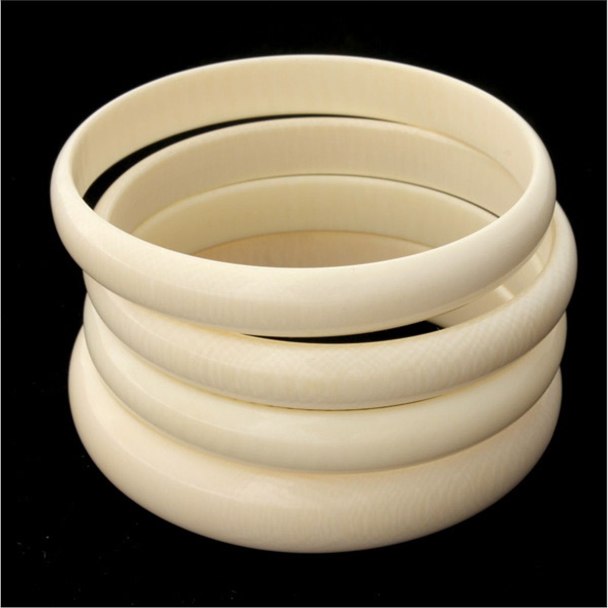 COLLECTION OF FOUR CARVED IVORY BANGLES.