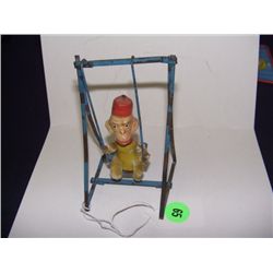 very old child's swinging monkey toy on metal swing frame