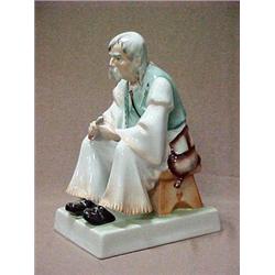 Porcelain figurine of a seated old man on r