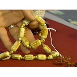 Chinese, carved and stained ivory prayer bead necklace with scrimmed figural and inscription designs
