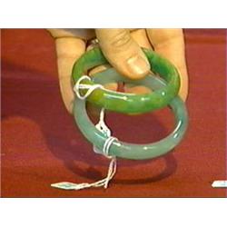 Two Chinese, carved jadeite bangle bracelets: apple-green and yellow and mottled apple-green (both c