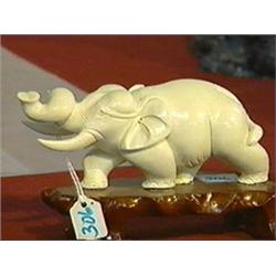 Well-carved, Chinese ivory model of an elephant with twisted trunk, wood stand