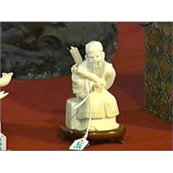 Small, Chinese carved ivory figure of a seated Immortal holding bamboo and carrying a parasol on his