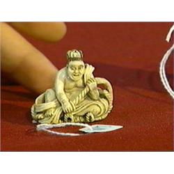 Well-detailed, carved and stained, ivory netsuke of a man seated on a huge sandal, signed "Meigyokus