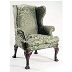 A George III mahogany wing back armchair, upholstered in green damask with brass studding, on leaf c