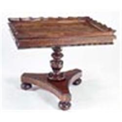 A George IV rosewood table, the rectangular top with a scroll carved gallery and nulled border on a