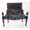 A cast iron serpentine fire grate in neoclassical style with scrolls and patera, urn finials and tap
