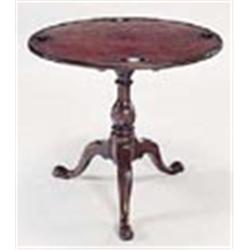 A George III mahogany and fruitwood games table, the round tilt top with four counter wells and a le