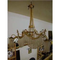 Large ornate gilt ceiling light with curtain drops and ribbon decoration.