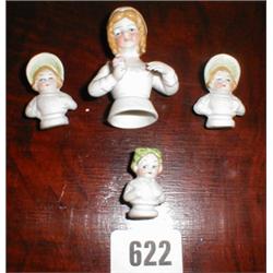 A set of four porcelain miniature pin doll...