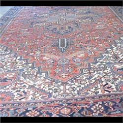 Heriz Oriental rug. The center medallion is in shades of red, blue,  and rust colors on a red ground
