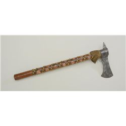 Cast iron axe head with wood shaft that is  decorated with what appears to be copper  coins and bras