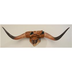 Old pair of steer horns and a hoof mounted on  wood board with hide covering that is  deteriorating 