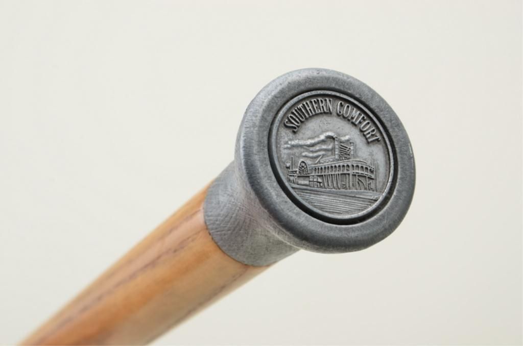 Advertising wood walking stick with metal head displaying Southern Comfort paddle wheel boat emble