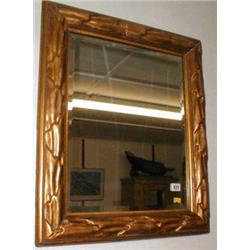 A bevel-edged mirror in gilt stucco frame...