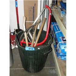 Green garbage bin filled with assorted saws, axes grease guns etc