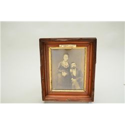 Antique photo of man and woman in wood frame  approx. 12” x 10” overall with label on front  “Origin