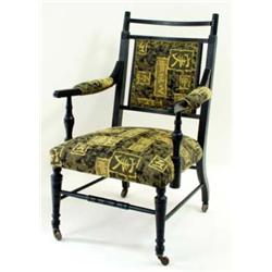 AN EBONISED EDWARDIAN ARMCHAIR with reeded crest rail and upholstered back, the part upholstered arm