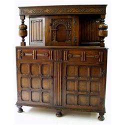 A CARVED OAK COURT CUPBOARD the top with trailing vine frieze on baluster end supports, the central.