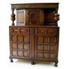 A CARVED OAK COURT CUPBOARD the top with trailing vine frieze on baluster end supports, the central.