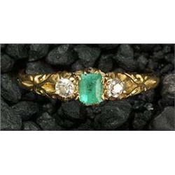An Edwardian 18ct gold, small emerald and diamond three stone ring, the central trap-cut emerald cla