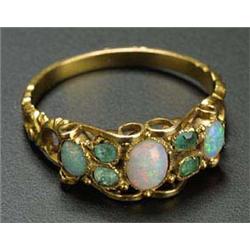 A Victorian gold, opal and emerald ring, centred with an oval white opal between pairs of small pale