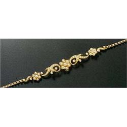An Edwardian gold and half-pearl necklace of three graduated flower-head clusters with scroll inters