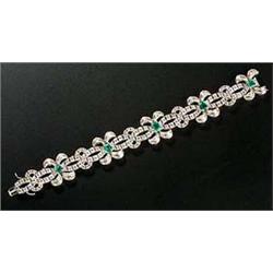 An Italian emerald and diamond bracelet of two wavy lines of round brilliant diamonds with five twin