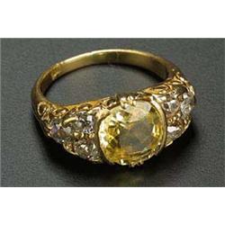 An early 20th century gold, yellow sapphire and diamond carved ring, centred with a cushion-shaped m
