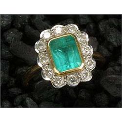 A modern 18ct gold, emerald and diamond oblong cluster ring, the central emerald-cut emerald, rub-ov