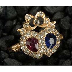 An Edwardian ruby, sapphire and diamond twin hearts ring with a ribbon bow surmount, each heart cent