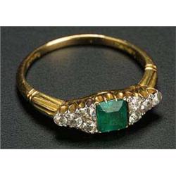 An Edwardian gold, emerald and diamond ring, centred with a square trap-cut emerald, claw set betwee