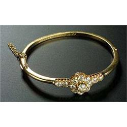 An Edwardian gold and diamond bangle, the front designed as a cluster with a centre stone approx. 0.