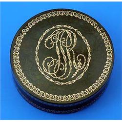 An early 19th century tortoiseshell round box, with pique work scrolling borders, the cover with a m