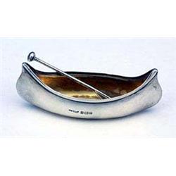 A salt cellar in the form of a canoe with paddle shaped spoon, the canoe Birmingham 1904 the spoon L