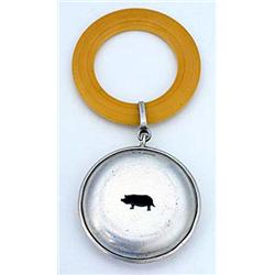 A silver child's rattle, compressed round and pierced with a pig, suspended from a plastic teether,.