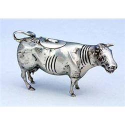 A Dutch cow creamer, the head with ruby-glass eyes, the hinged cover with a fly finial, the curling.