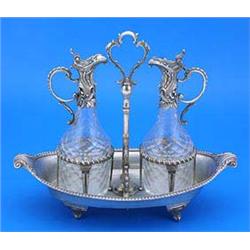 A Victorian oil and vinegar frame, oval with a nulled border, volute terminals and scroll feet, a ce