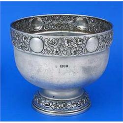 A round punch bowl, the border embossed with trailing flowers, leaves and roundels, on a domed foot.
