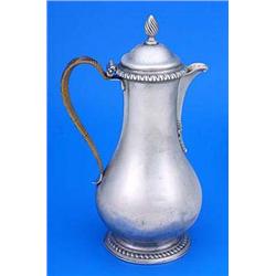 A George III pear shaped hot water jug, with a leaf chased spout, cane wrapped handle, domed cover w