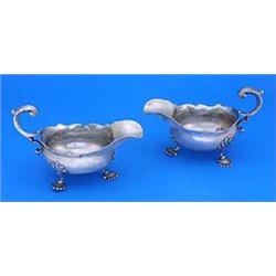 A pair of George II sauce boats, each with a shaped border, leaf capped flying scroll handle on shel