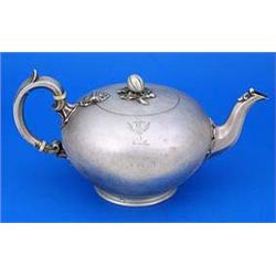 A Victorian bullet shaped teapot, engraved with a crest with a facetted leaf capped spout and flush.