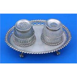 A George III oval inkstand with gadrooned and pierced borders on four ball and claw feet, with a cut