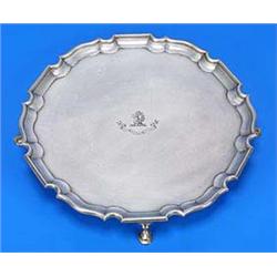 A Victorian round salver with a shaped border on four hoof feet, engraved with a crest and motto, Lo
