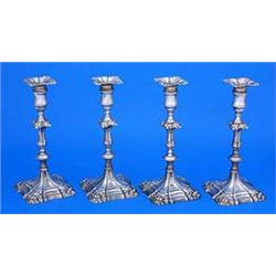 A set of four late George II cast candlesticks, the knopped columns and the shaped square spreading.