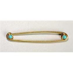 A gold and turquoise brooch, resembling a safety pin, set at each end with a small turquoise cabocho