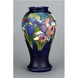 A Moorcroft baluster vase, decorated in naturalistic colours with orchids and irises against a deep.